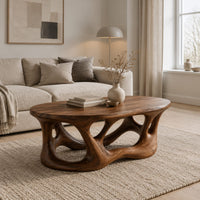 Oval coffee table with a branching root shaped base full of irregular openings in a Scandinavian living room with white walls
