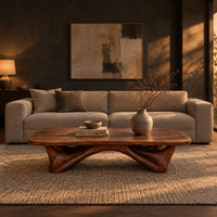 Low coffee table with a carved organic base and a soft edged top in a dark living room at golden hour