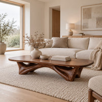 Low coffee table with a carved organic base and a soft edged top in a Scandinavian living room with white walls