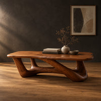 Coffee table with an irregular soft edged top on sculpted branching legs in a dark studio against a charcoal plaster wall