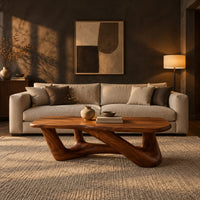 Coffee table with an irregular soft edged top on sculpted branching legs in a dark living room at golden hour