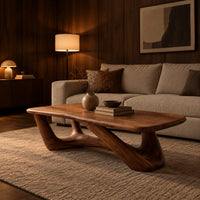 Coffee table with an irregular soft edged top on sculpted branching legs in an evening living room with walnut wall paneling