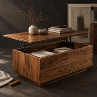 Corner detail of boxy wooden coffee table with a lift up top on dark hinged arms beside wood, brass and linen samples