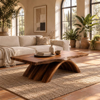 Coffee table with a natural edge top on a fanned arch base in a bright living room with arched windows and plants