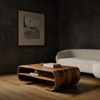 Coffee table with rolled ends and a double open shelf in a dark studio against a charcoal wall