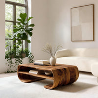 Coffee table with rolled ends and a double open shelf in a sunlit room with large windows and plants