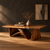 Coffee table with a tapered block pedestal and a swooping wood loop in a dark studio against a charcoal plaster wall