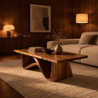 Coffee table with a tapered block pedestal and a swooping wood loop in an evening living room with walnut wall paneling