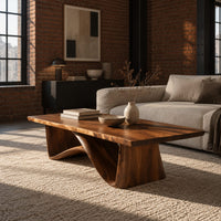 Coffee table with a tapered block pedestal and a swooping wood loop in an industrial loft living room with exposed brick