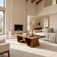 Coffee table with a tapered block pedestal and a swooping wood loop in a bright open plan living room