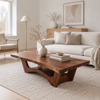 Coffee table with a thick slab top and arched pedestal legs in a Scandinavian living room with white walls