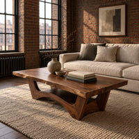 Coffee table with a thick slab top and arched pedestal legs in an industrial loft living room with exposed brick