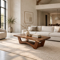 Coffee table with a thick slab top and arched pedestal legs in a bright open plan living room