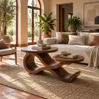 Wooden coffee table with two circular tops on a swooping ribbon base in a bright living room with arched windows and plants