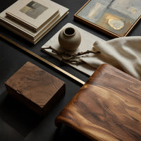 Corner detail of compact loop coffee table with a small drawer beside wood, brass and linen samples