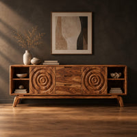 Sideboard with ring carved panels and open end shelves on angled legs in a dark studio against a charcoal plaster wall