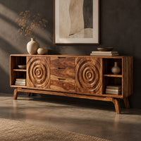 Corner detail of sideboard with ring carved panels and open end shelves on angled legs beside wood, brass and linen samples