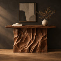 Console table with a deeply ridged sculpted block base in a dark studio against a charcoal plaster wall