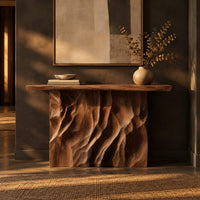 Console table with a deeply ridged sculpted block base in a dark entryway at golden hour