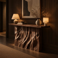 Console table with a deeply ridged sculpted block base in an evening entryway with walnut wall paneling