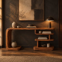 Long console table with a bent side panel and stacked open shelves in a dark entryway at golden hour