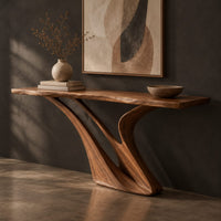 Corner detail of console table with a slim top on a sculpted swooping base beside wood, brass and linen samples