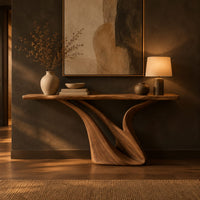 Console table with a slim top on a sculpted swooping base in a dark entryway at golden hour