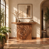 Console table with a spiral carved front and a slab top in a bright entryway with arched windows and plants
