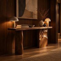 Console table with a slab top and one leg carved in flowing waves in an evening entryway with walnut wall paneling