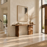Console table with a slab top and one leg carved in flowing waves in a bright open plan entryway
