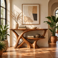 Wooden console table with a branching root base and a small lower shelf in a bright entryway with arched windows and plants