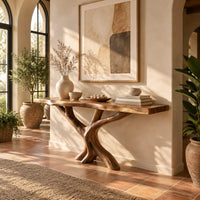 Console table with a thin natural edge top on a branching trunk base in a bright entryway with arched windows and plants