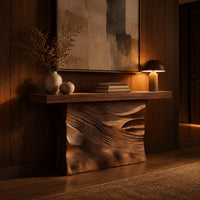 Console table with a solid block base carved in dune ripples in an evening entryway with walnut wall paneling