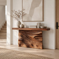 Console table with a solid block base carved in dune ripples in a Scandinavian entryway with white walls