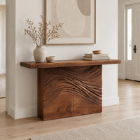 Console table with a thick plank top and wave carved block base in a Scandinavian entryway with white walls