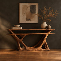 Console table with a double layer top and a branching open base in a dark studio against a charcoal plaster wall