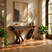 Console table with a double layer top and a branching open base in a bright entryway with arched windows and plants