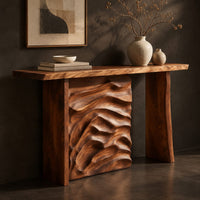 Corner detail of console table with plank legs and a dune carved panel beside wood, brass and linen samples