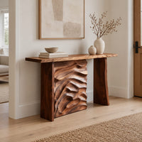 Console table with plank legs and a dune carved panel in a Scandinavian entryway with white walls