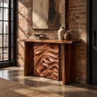 Console table with plank legs and a dune carved panel in an industrial loft entryway with exposed brick