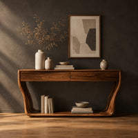 Console table with flared sculpted sides, a low shelf and two drawers in a dark studio against a charcoal plaster wall