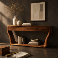 Corner detail of console table with flared sculpted sides, a low shelf and two drawers beside wood, brass and linen samples