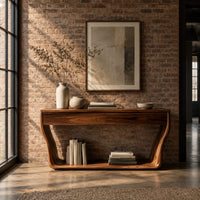 Console table with flared sculpted sides, a low shelf and two drawers in an industrial loft entryway with exposed brick