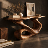 Corner detail of narrow console table with a flowing s shaped base and an open loop foot beside wood, brass and linen samples