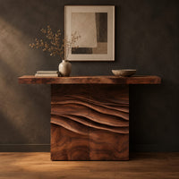Console table with a thick top on a wave carved block base in a dark studio against a charcoal plaster wall