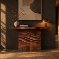 Console table with a thick top on a wave carved block base in a dark entryway at golden hour