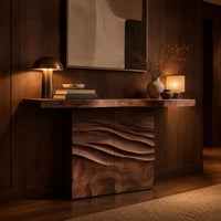 Console table with a thick top on a wave carved block base in an evening entryway with walnut wall paneling