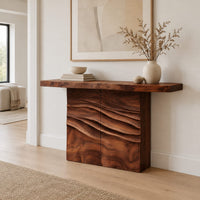Console table with a thick top on a wave carved block base in a Scandinavian entryway with white walls