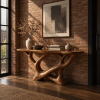 Oval top console table on a sculpted base of looping open limbs in an industrial loft entryway with exposed brick