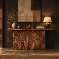 Console table on a block base carved with rippled ridges in a dark entryway at golden hour